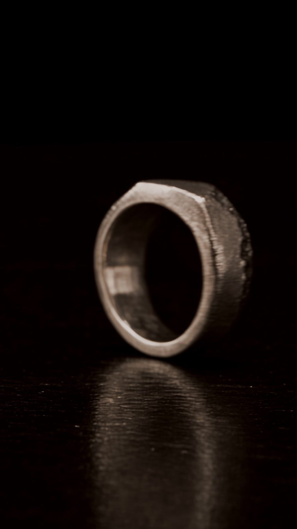 Textured silver ring standing on dark wood
