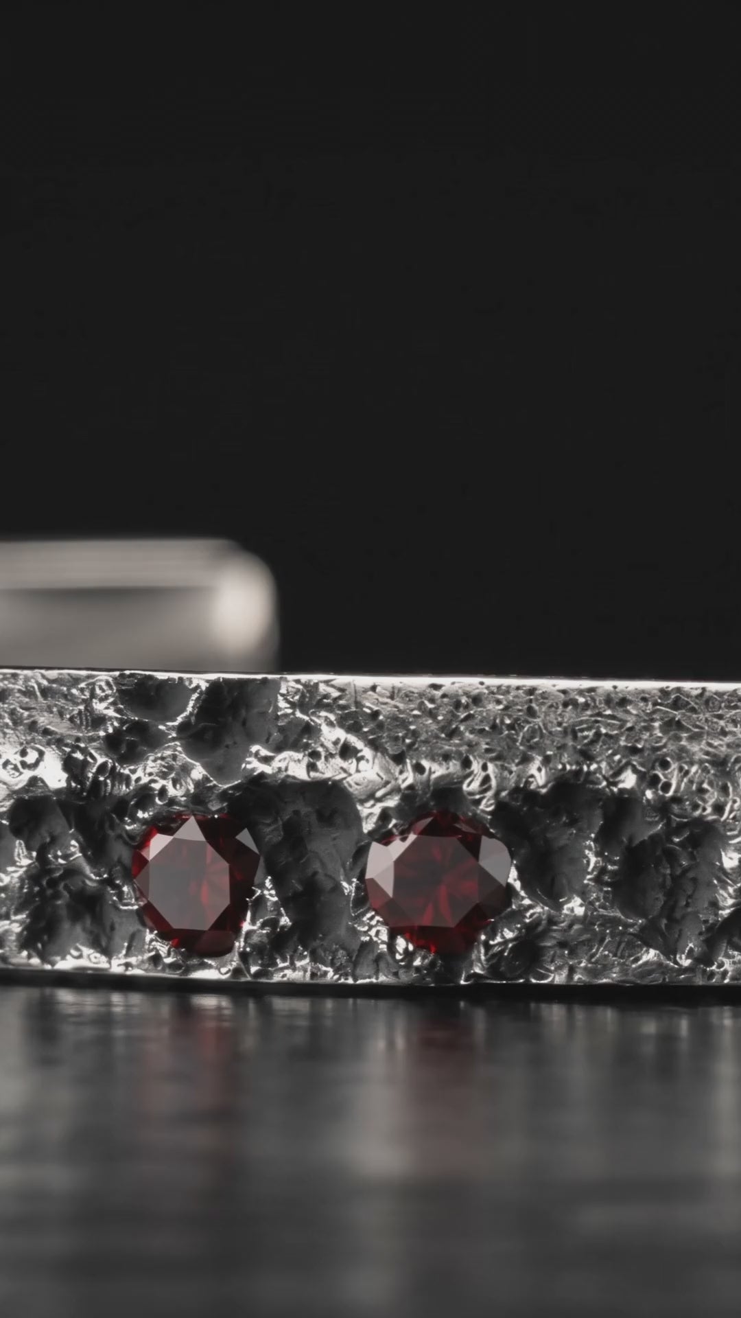 Raw III Bracelet, video tracking along the cuff's eroded silver face and the red garnets set into it