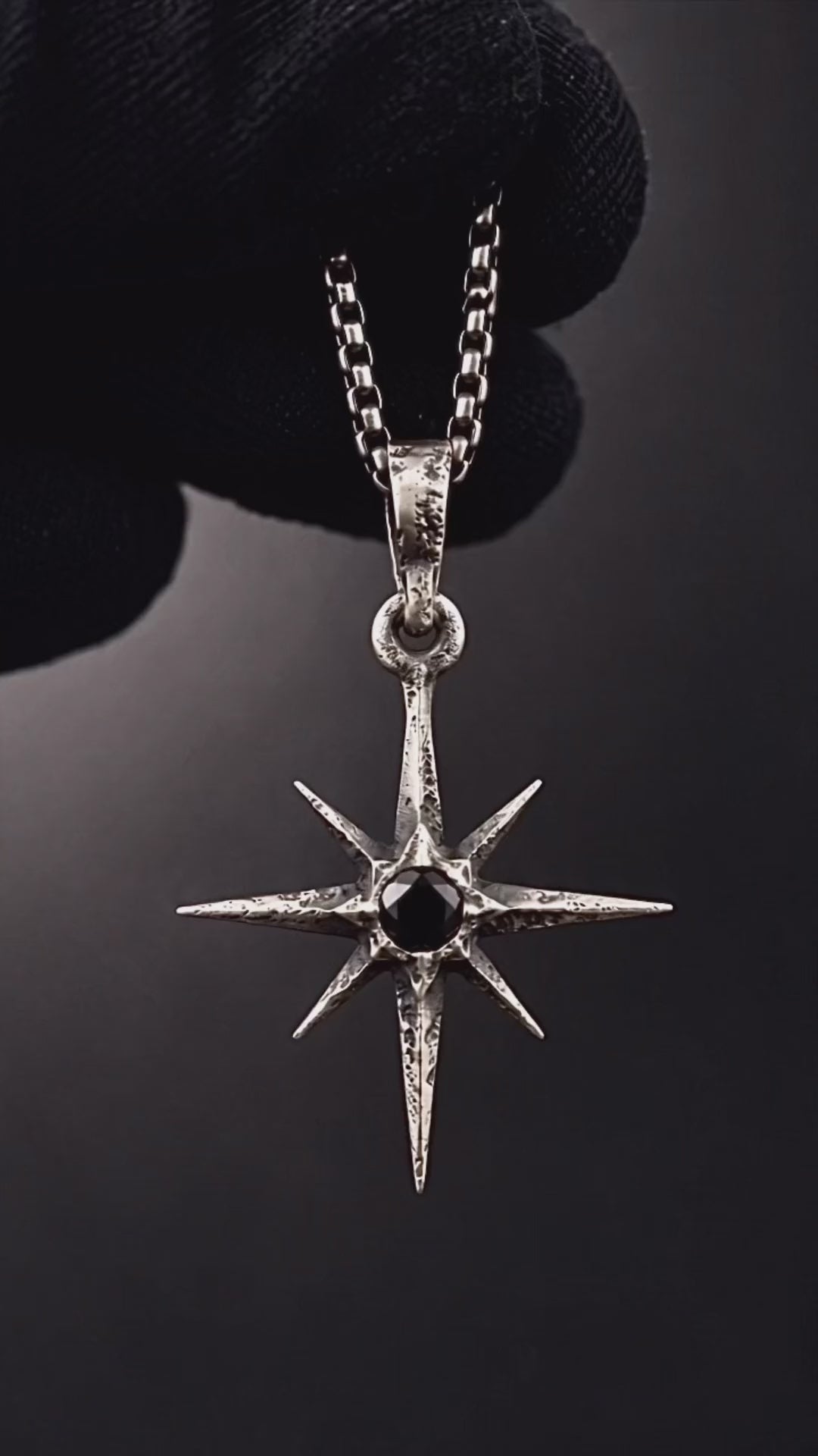 Raw IV Pendant shown in a black-gloved hand: the small eight-point star with its black stone, turned round to the RR star and 925 hallmarks on the back