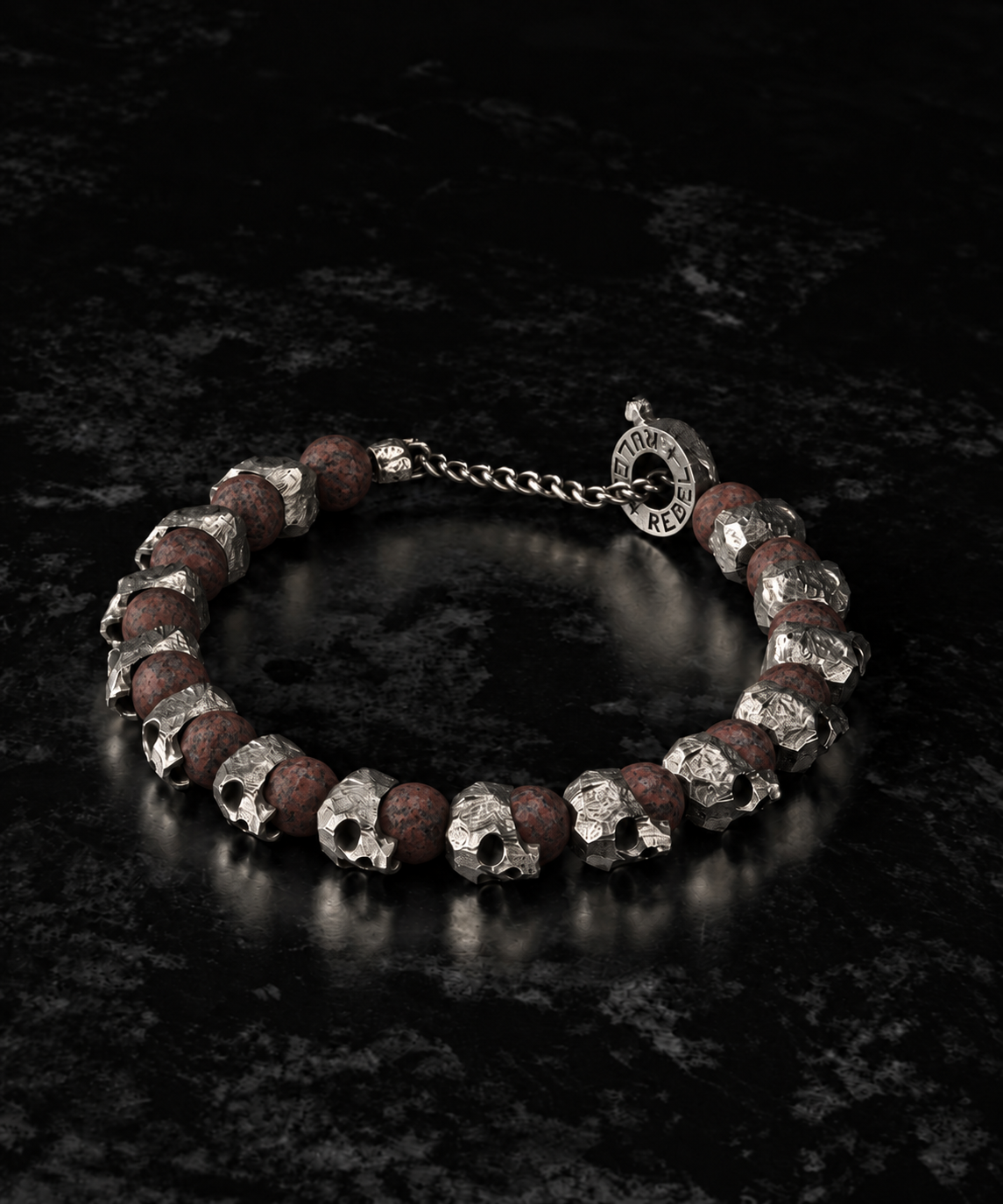 Raw I Bracelet, Red Brecciated Matte and skull beads laid in a circle on dark stone