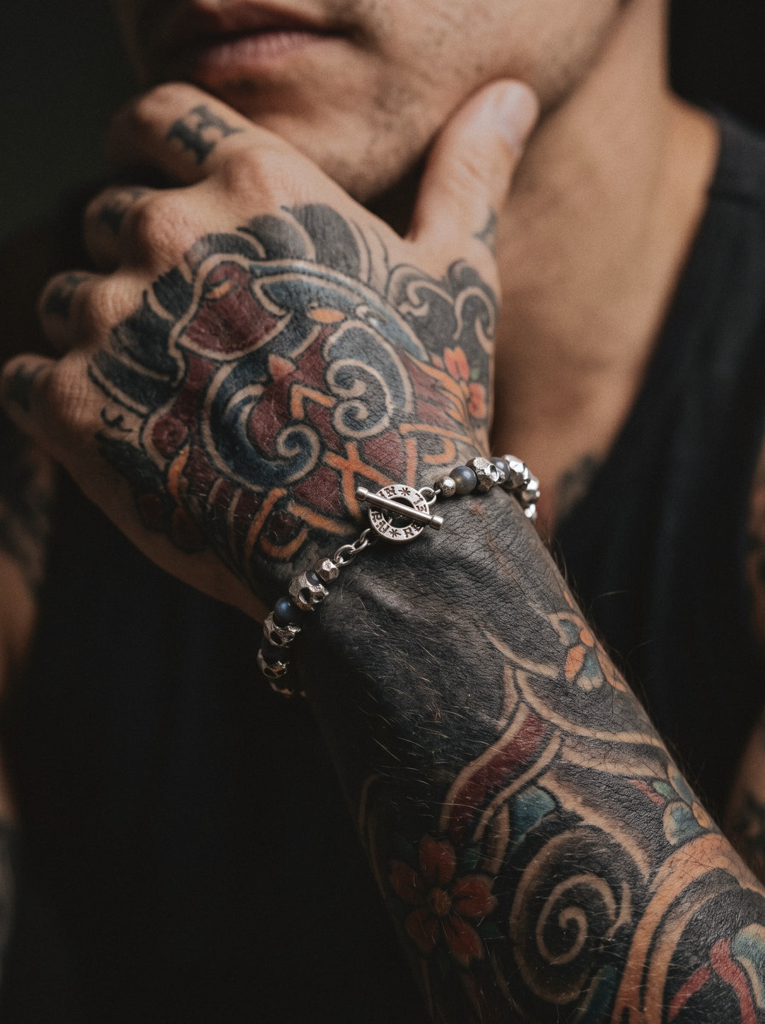 Raw I Bracelet with labradorite beads, silver skulls and its toggle clasp, worn on a man's wrist covered in Japanese tattoos