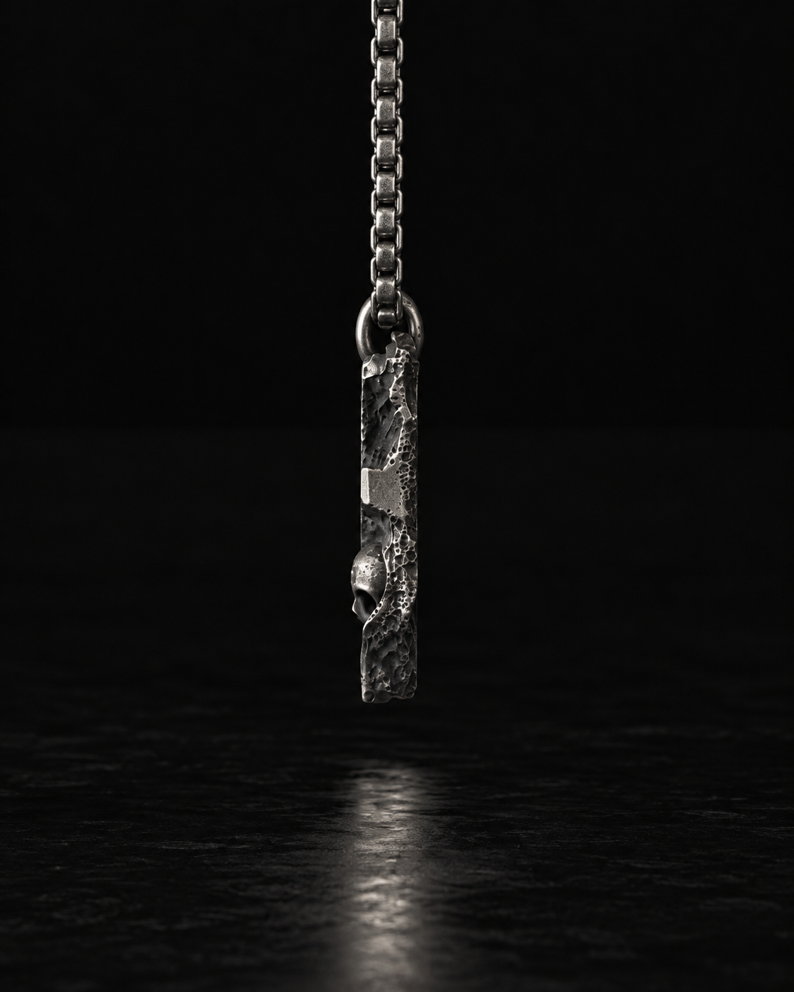Raw I Pendant seen edge on, a thin slab hanging from the chain
