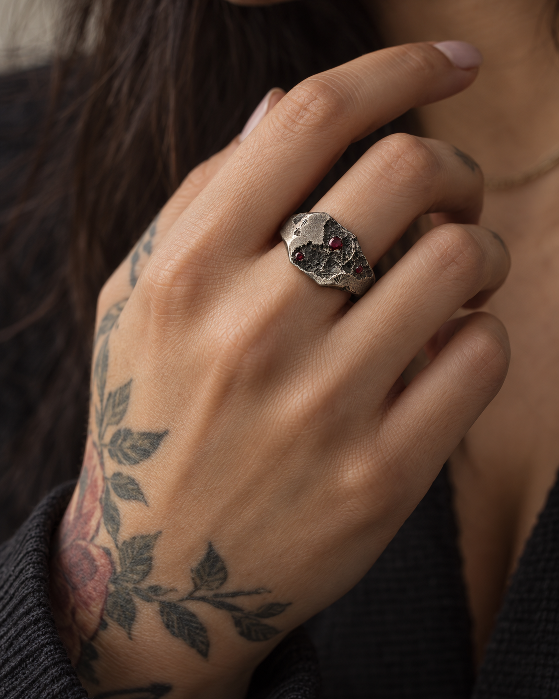 Raw I Ring worn on a woman's tattooed hand, red stones facing up