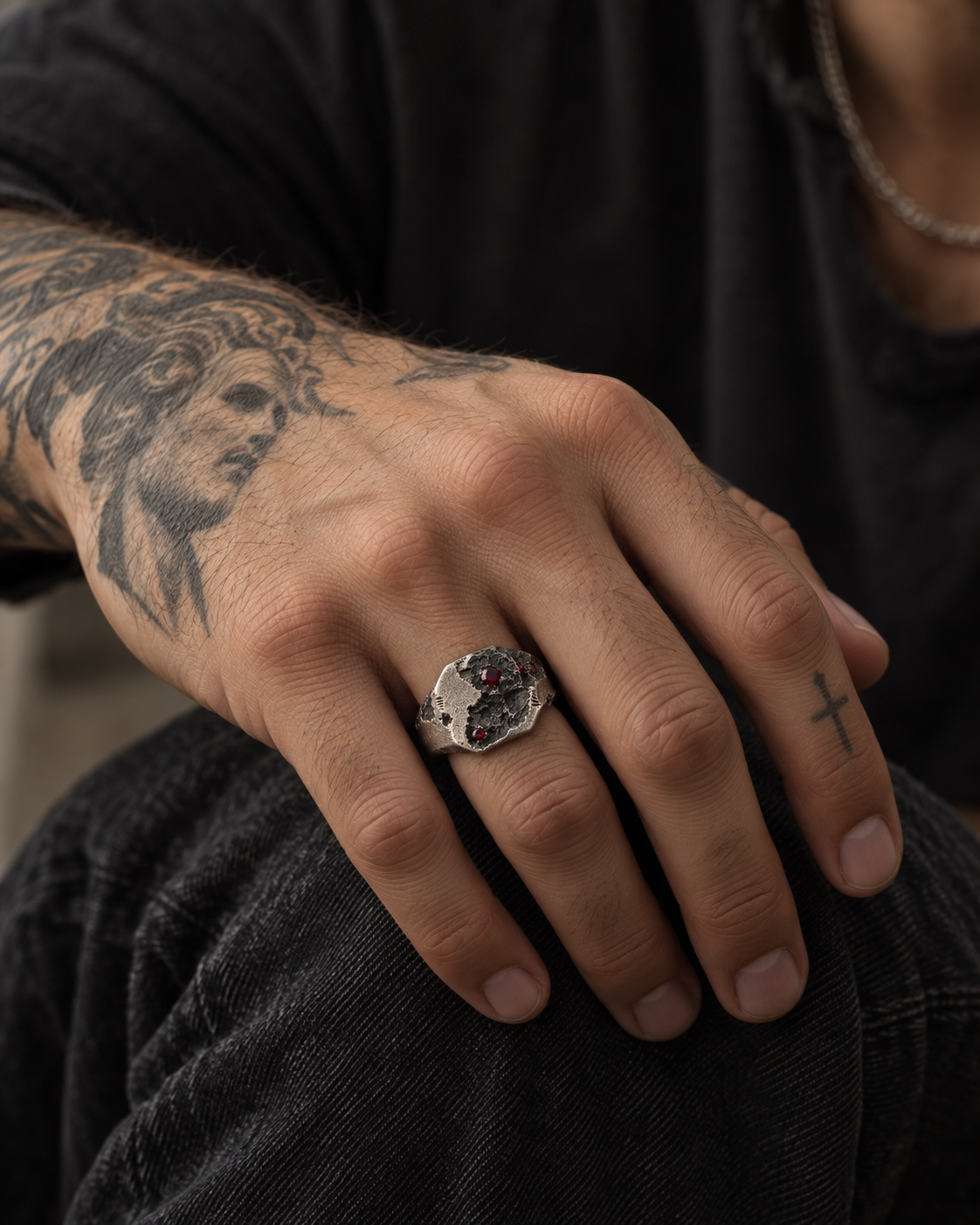 Raw I Ring on a man's hand, tattooed forearm and black shirt behind