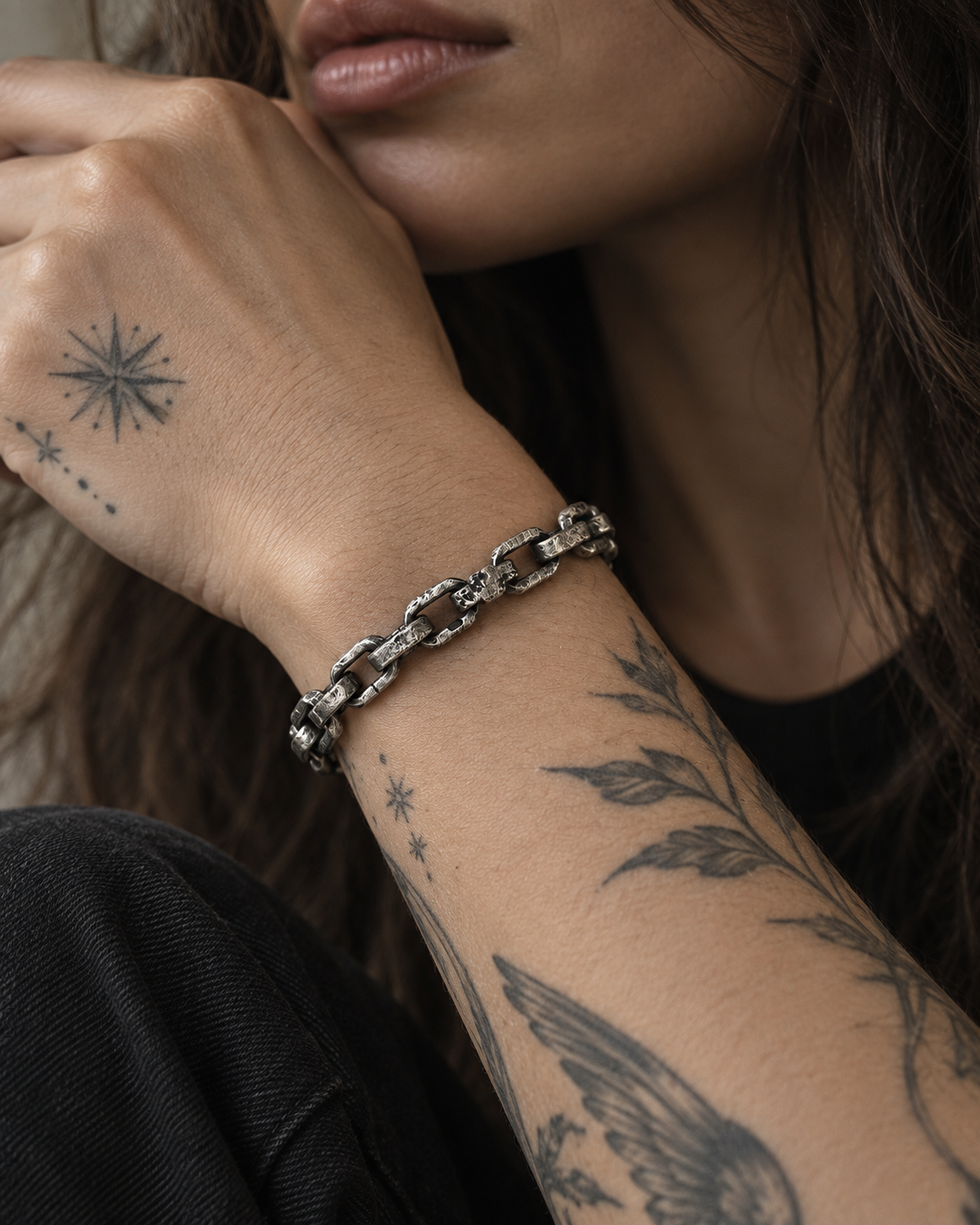 Raw II Bracelet on a woman's tattooed forearm, hand raised to her chin, black tank top