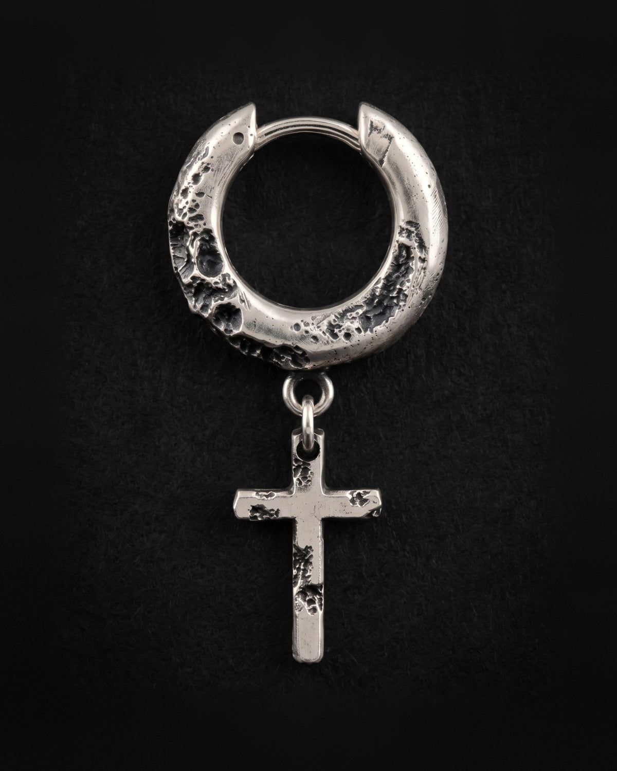 Raw II Earring from the front, the cratered silver hoop and the small cross hanging straight from two rings