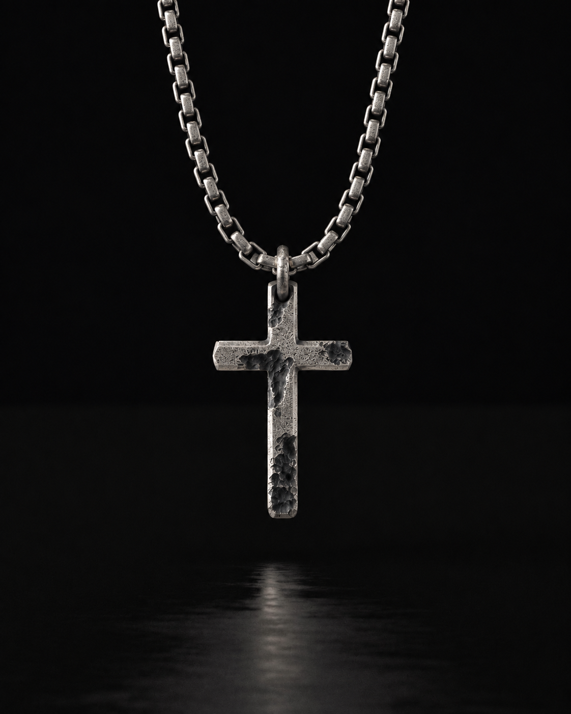 Raw II Pendant, a rough silver cross on a box chain against black