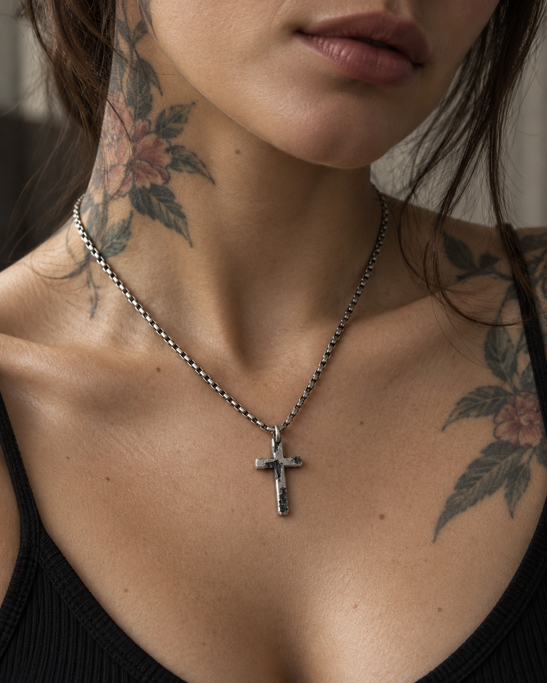 Raw II Pendant worn on a tattooed neck, the cross resting below the collarbones