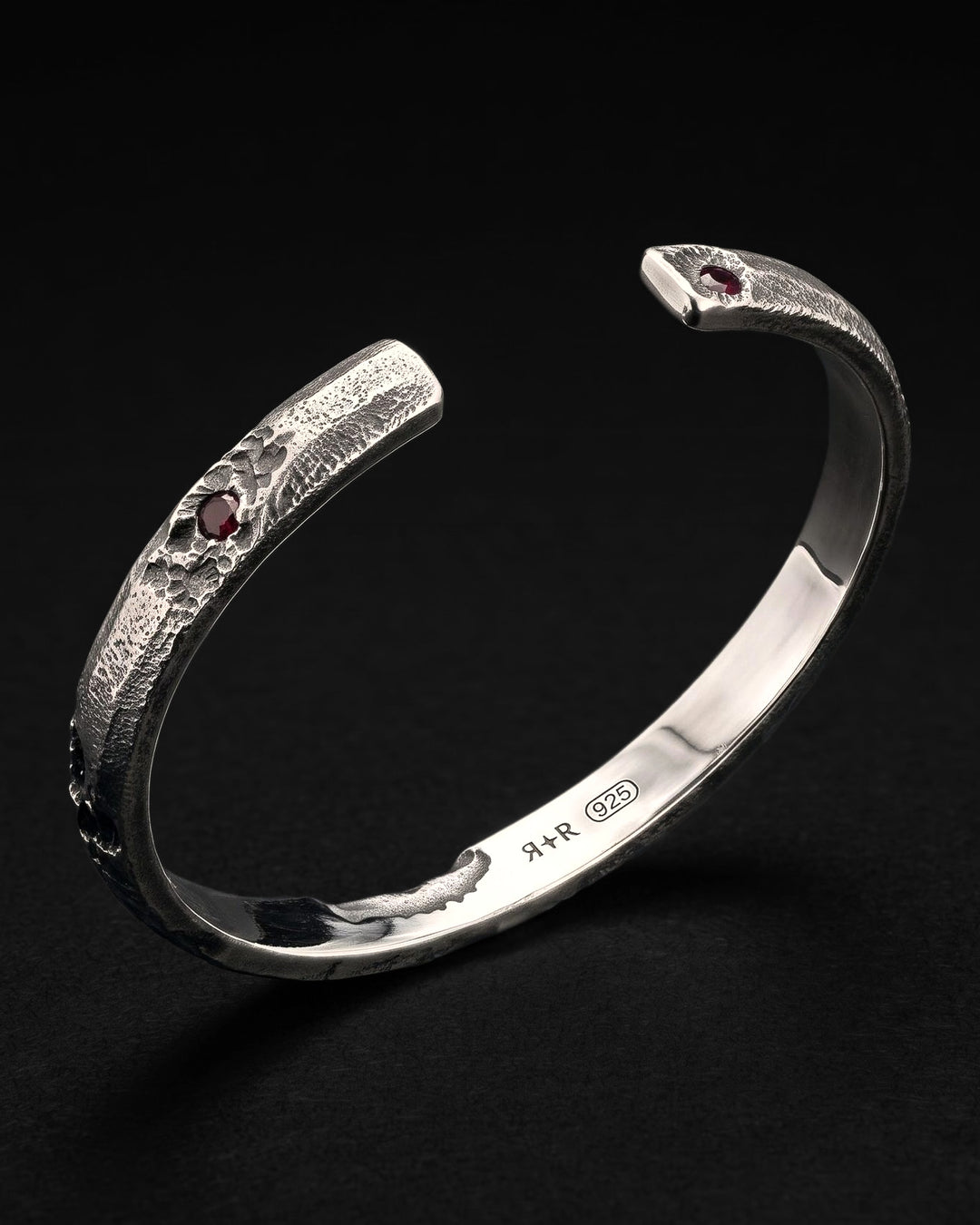 Raw III Bracelet with the opening toward the camera, a red stone at each end and the RR star hallmark and 925 inside
