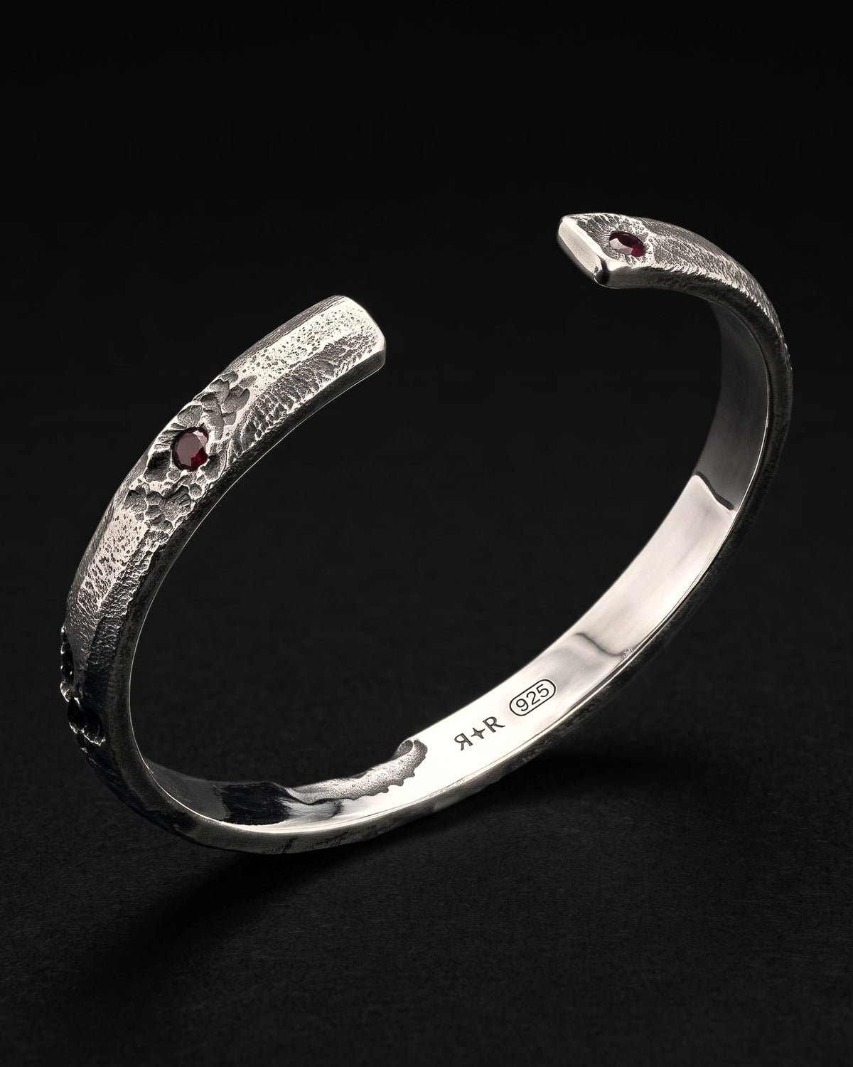Raw III Bracelet with the opening toward the camera, a red stone at each end and the RR star hallmark and 925 inside