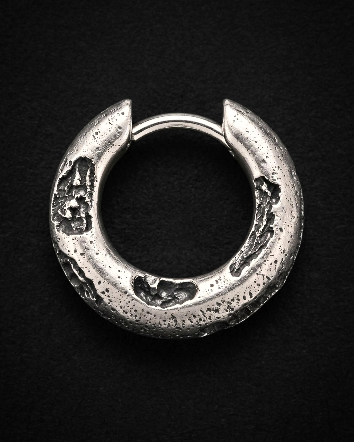 Raw III Earring from the front, black craters across the face of the silver hoop