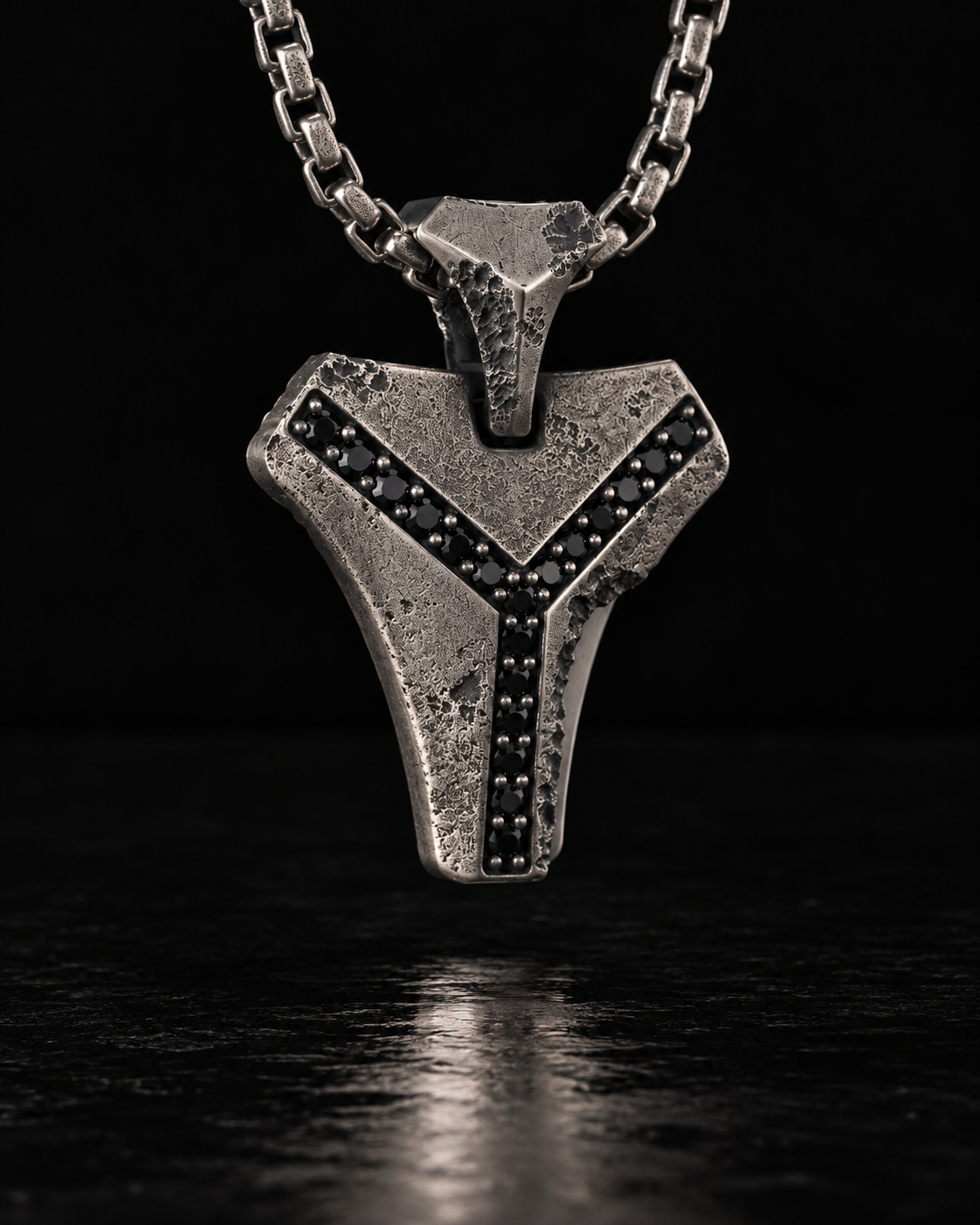 Raw III Pendant close up on its chain, pitted silver face and two lines of black stones