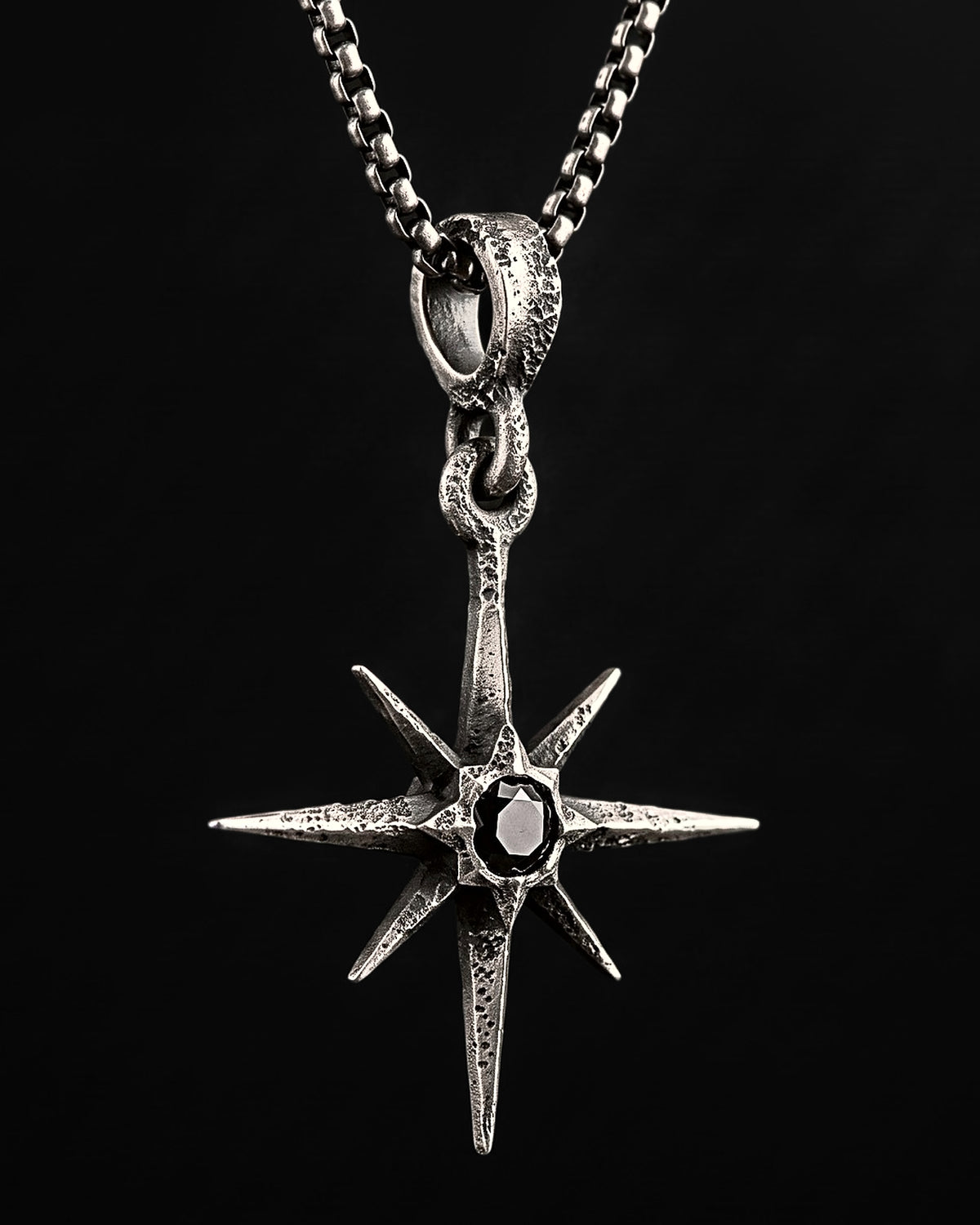 Raw IV Pendant at an angle, the faceted needles of the star, the black stone and the jointed bail on a box chain