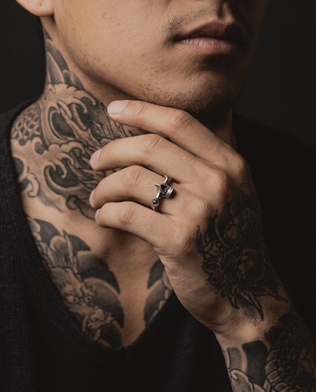Raw IV Ring worn by a man, his hand at his jaw, Japanese wave tattoos on his neck and a dragon on his hand