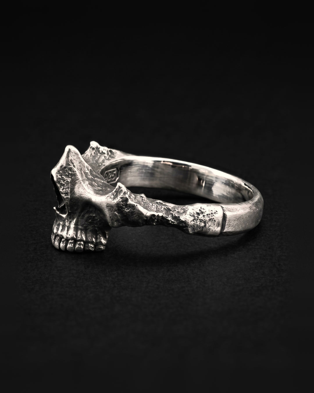 Raw IV Ring in side profile, the skull's teeth and cheekbone rising where the plain band begins