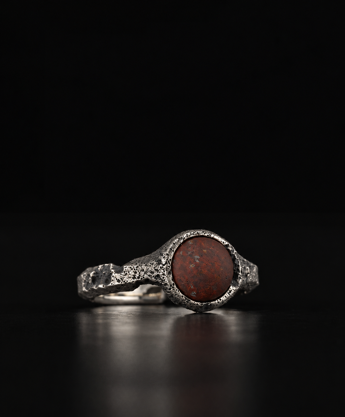 Raw VIII Ring turned to show the red brecciated stone and the rough band, on black