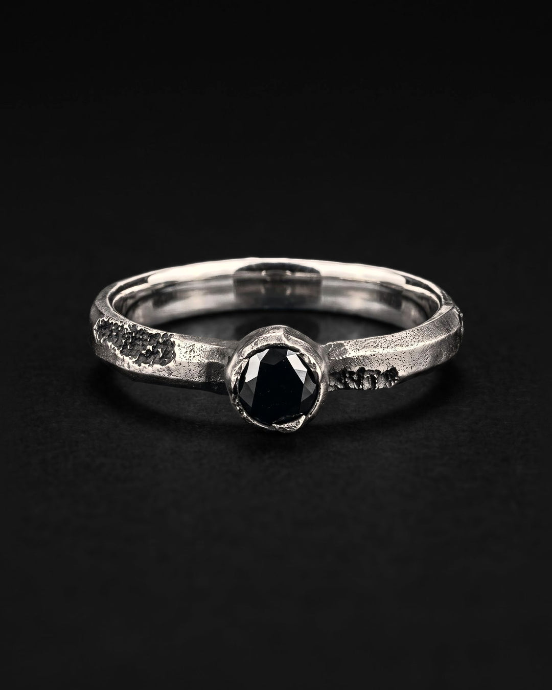 Raw XI Ring face on, the black stone in its bezel between pitted patches on the band