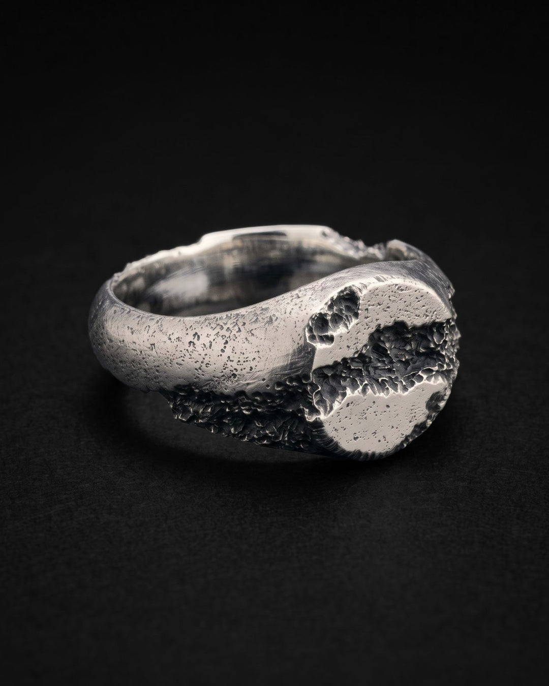 Raw XIV Ring at an angle on black, the crater breaking open the dome and running down the side