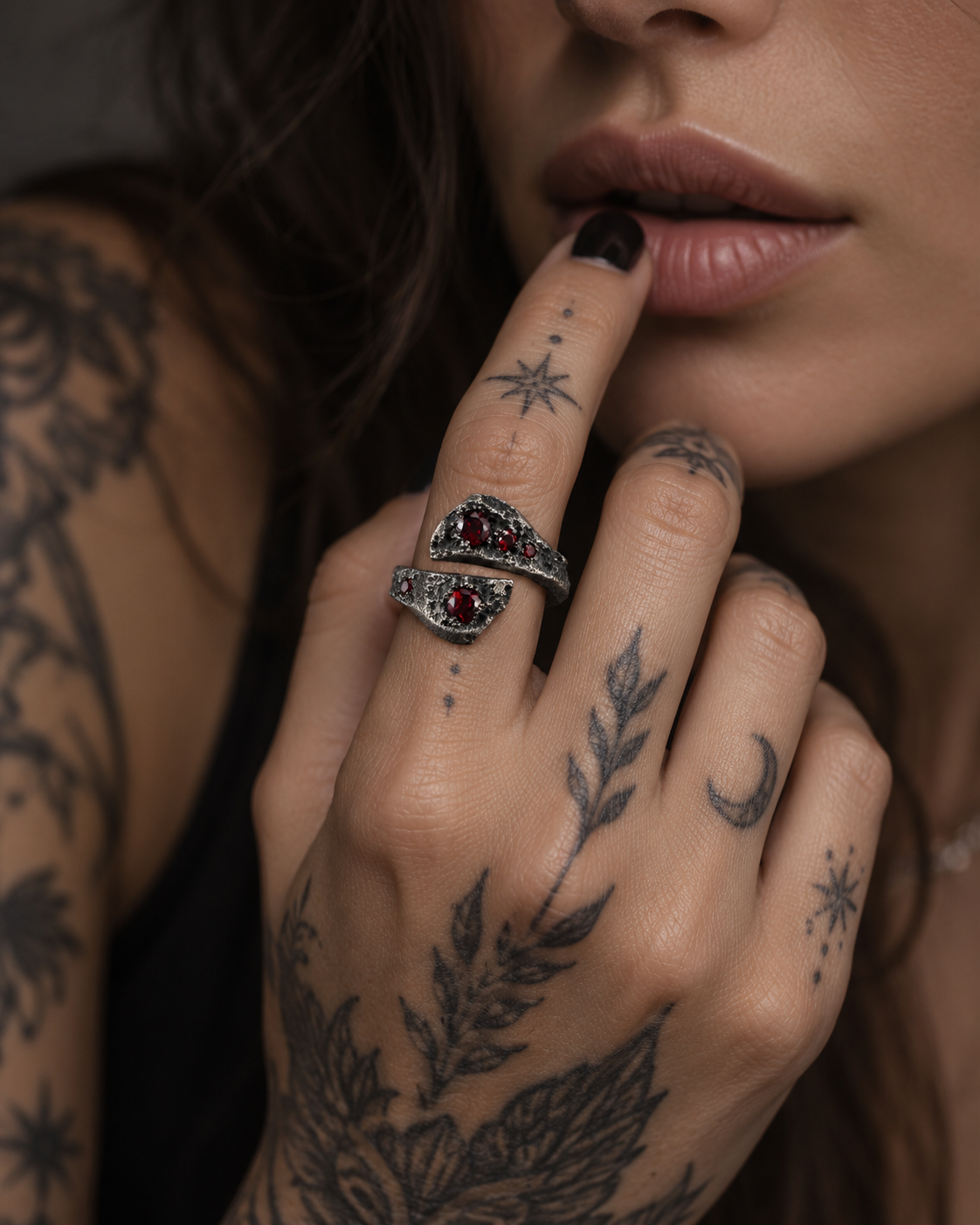 Raw XVII Ring with Ruby stones, worn on the index finger of a tattooed hand