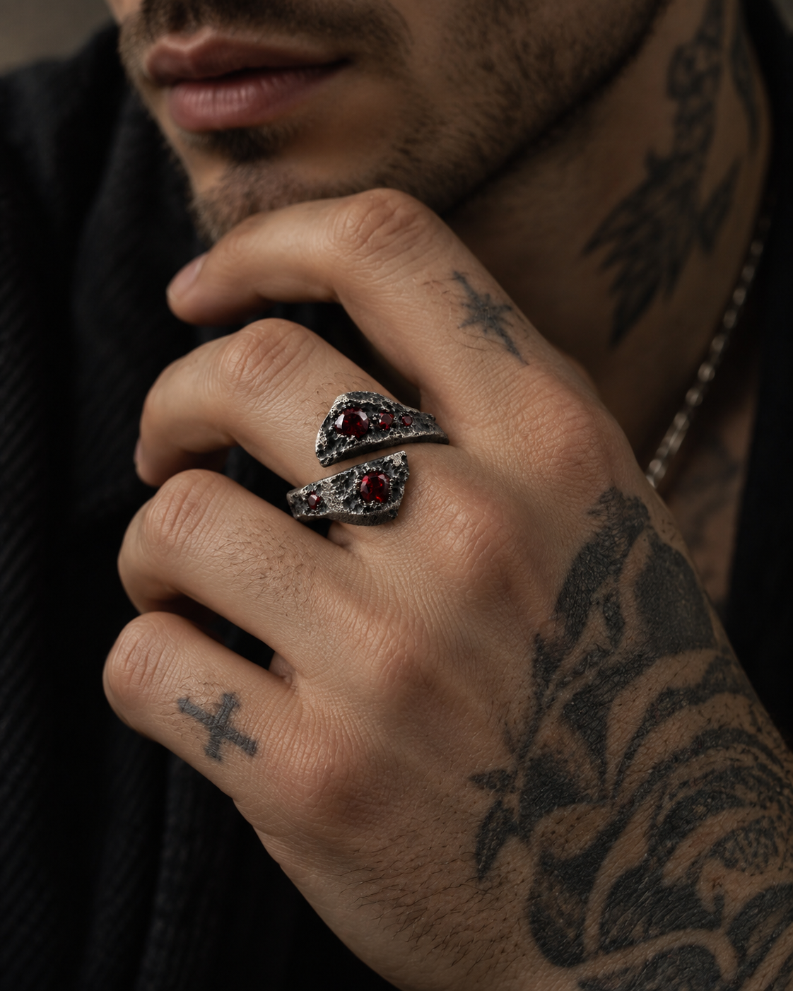 Raw XVII Ring with Ruby stones, on a tattooed hand held up to the chin, chain at the neck
