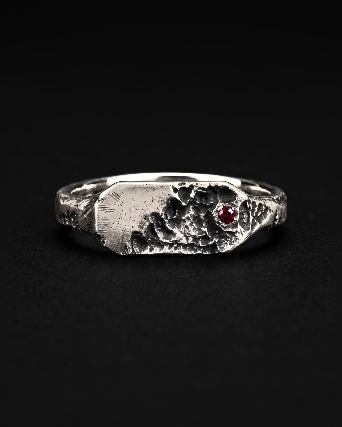 Raw XVIII Ring from the front, the smooth half of the face and the cratered half with a red stone