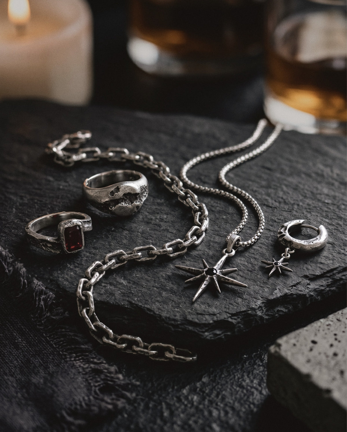 Ruby ring, cratered ring, link chain bracelet, star pendant and star hoop earring in raw silver on dark slate
