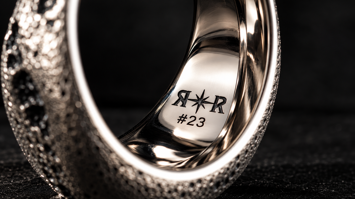 Silver ring standing on edge, the inside engraved with the R✦R mark and #23