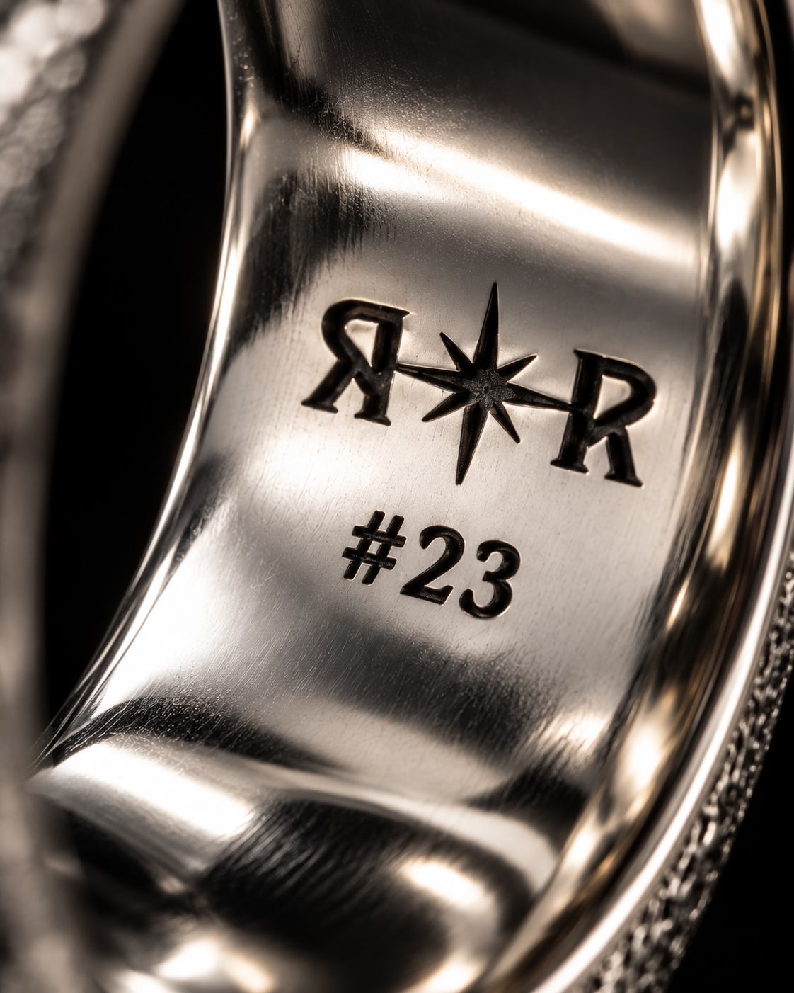 Inside of a silver ring engraved with the R✦R mark and the number 23