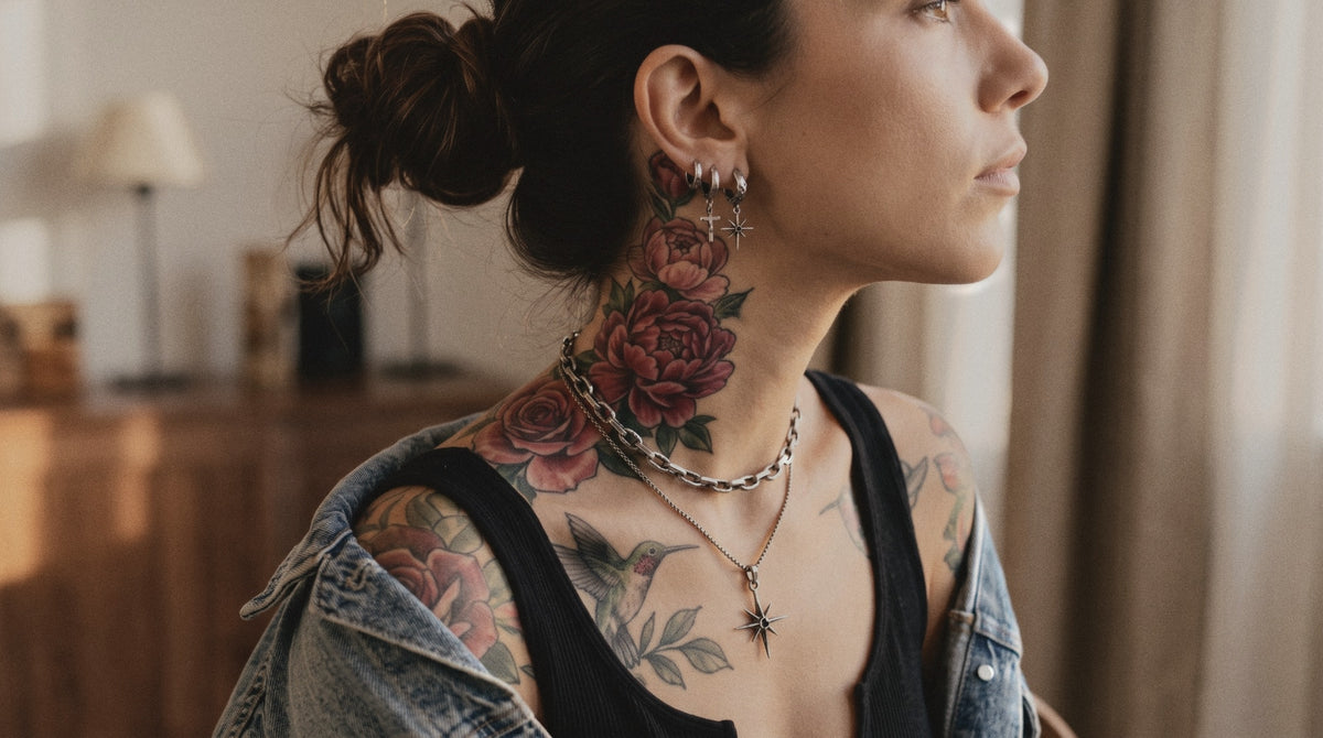 Tattooed woman in profile wearing three hoop earrings with a cross and a star, a link necklace and a star pendant in raw silver